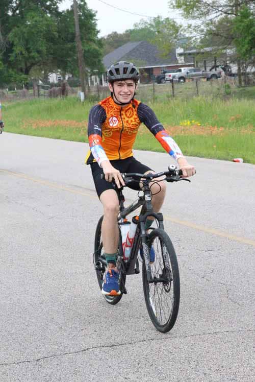 Bright young cyclist riding a bike on road, promoting Bluebonnet Express bike program.