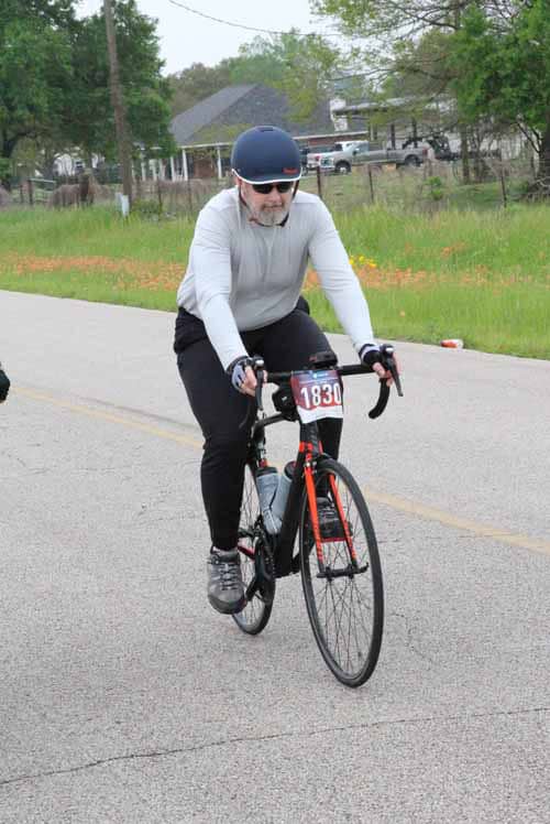 Cyclist participating in Bluebonnet Express charity bike race on scenic rural road.