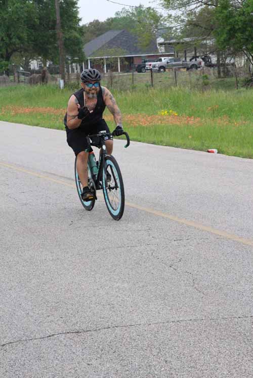 High-performance blue road bike cyclist on rural road during daytime.