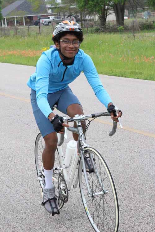 Bright young cyclist riding a road bike outdoors in casual sportswear for Bluebonnet Express.