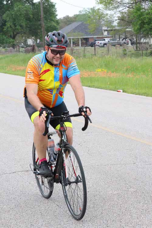 Vibrant cyclist riding on open road, Bluebonnet Express themed biking event.