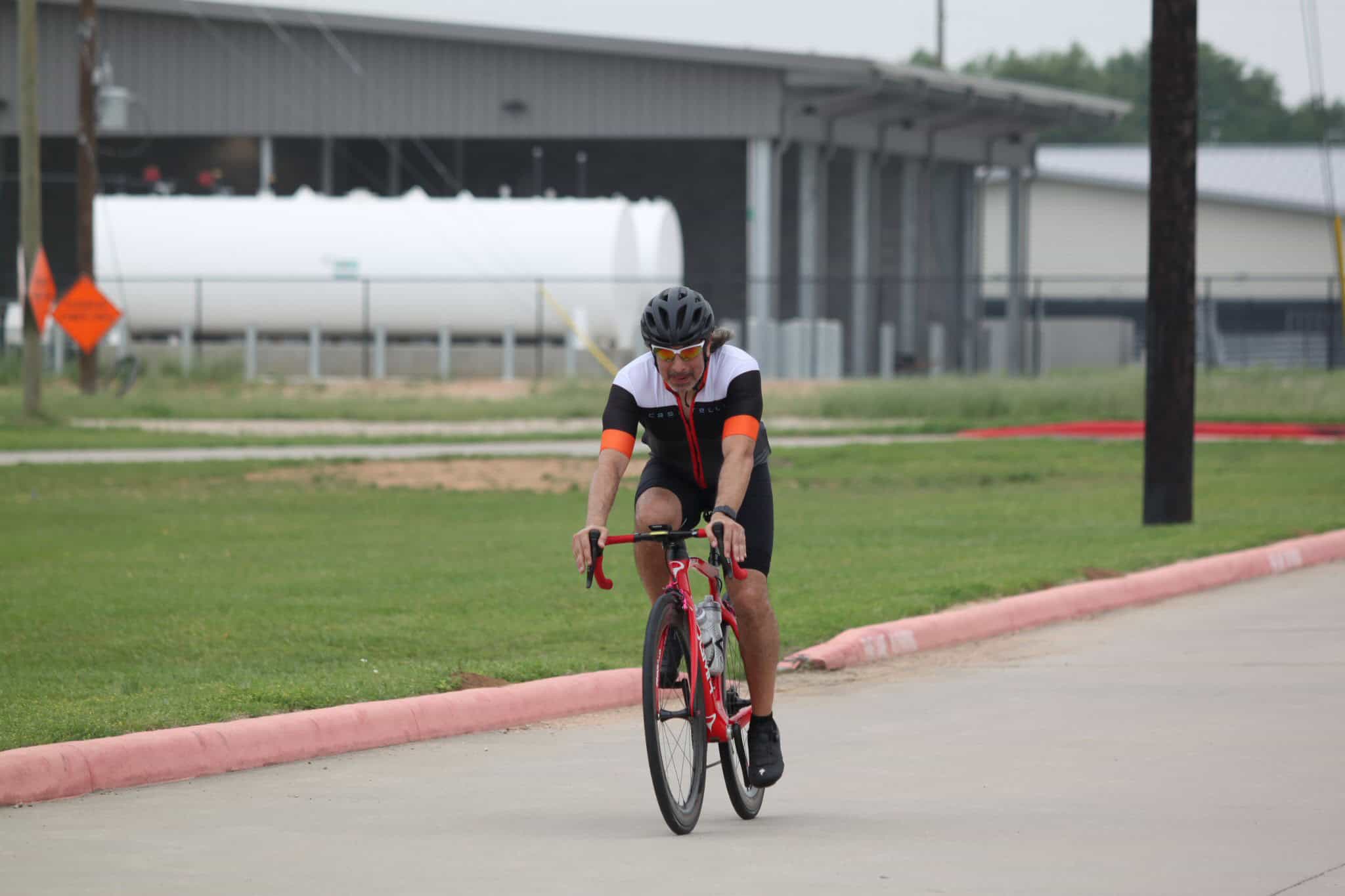 Cyclist riding a road bike outdoors on a paved path, showcasing endurance and cycling fitness.