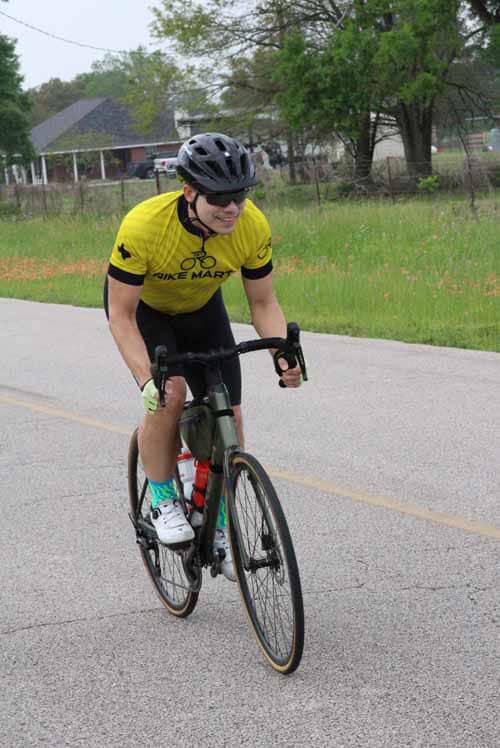 1. Man riding a bike in Yellow Jersey on a rural road during daytime.