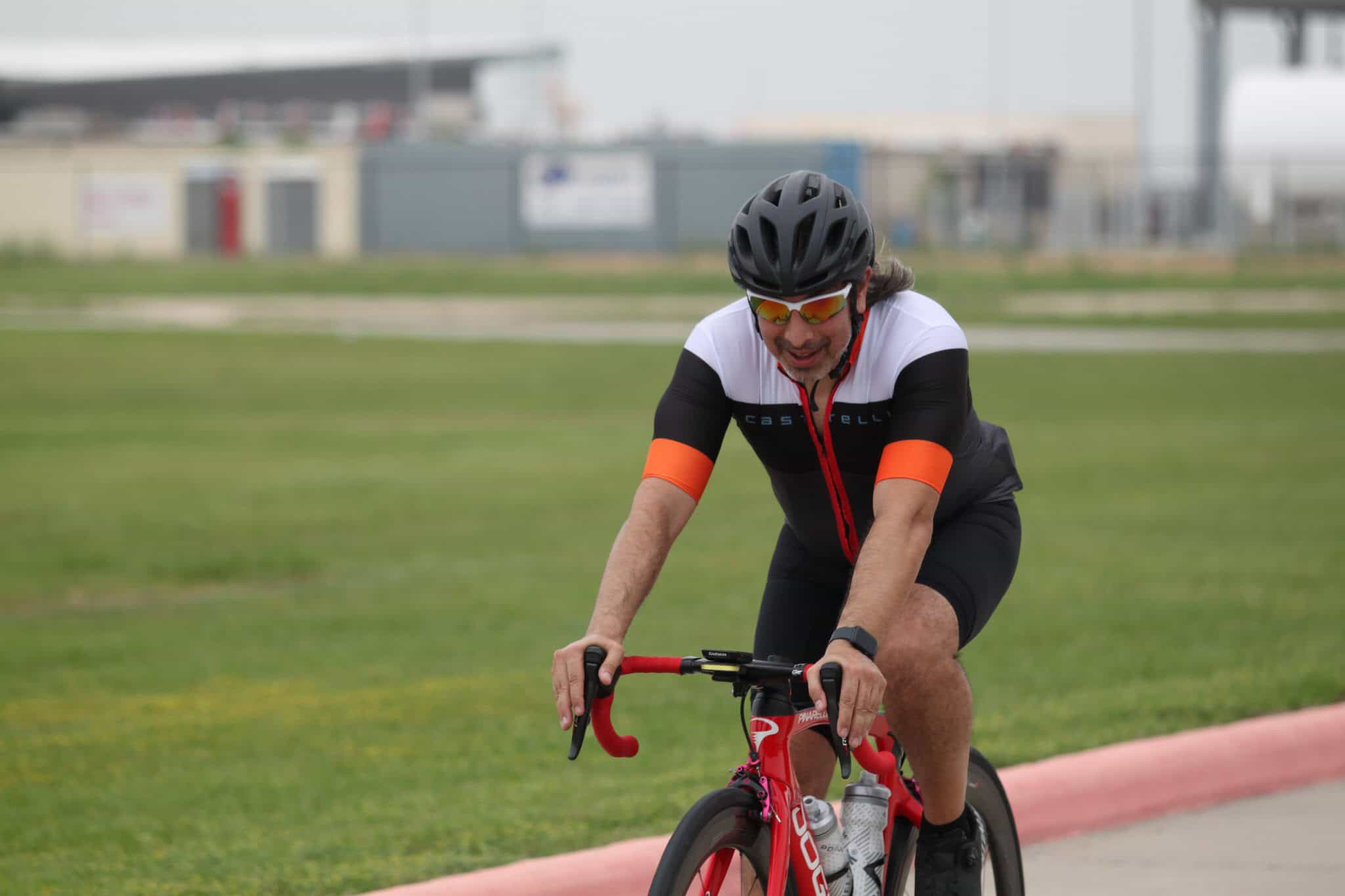 Man biking outdoors on a race track, promoting Bluebonnet Express cycling events.