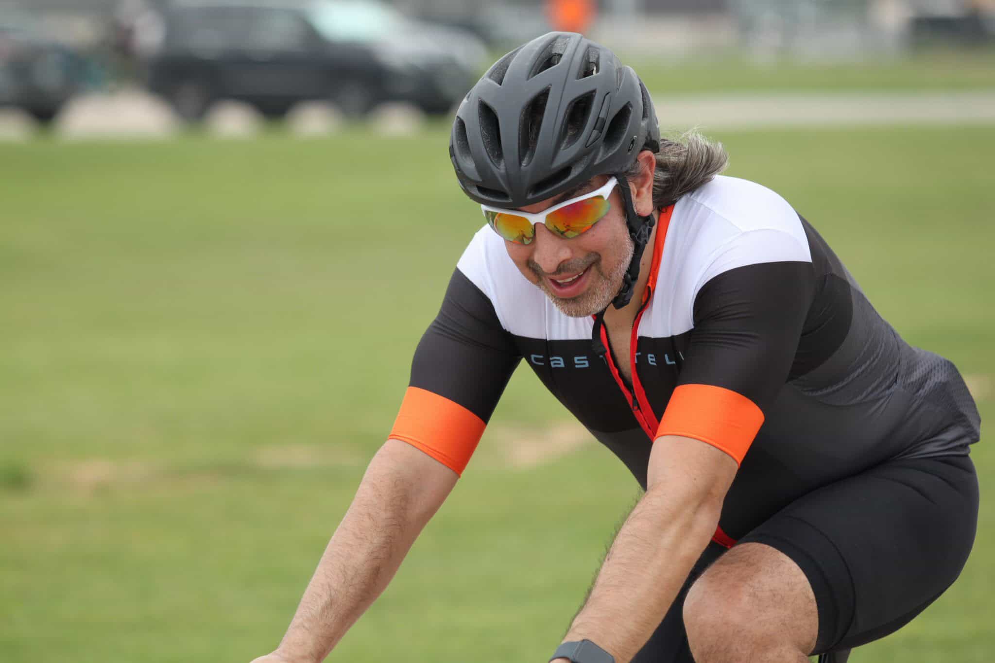 Vast helmeted cyclist with sunglasses enjoying outdoor riding, green park background.