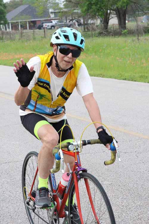 Endurance cyclist riding vintage road bike in colorful athletic gear during sunny outdoor ride.