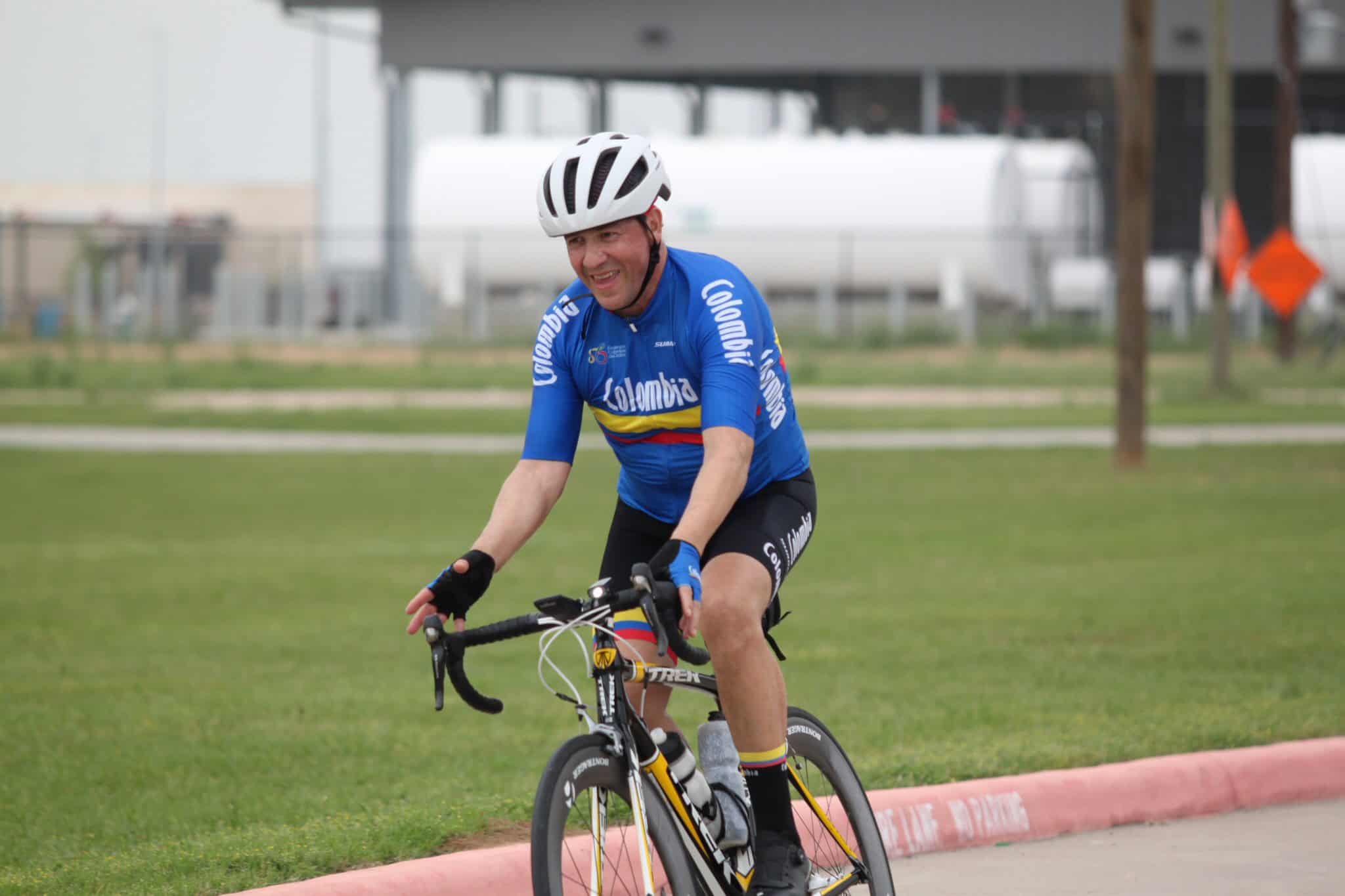 High-performance cyclist riding on a track wearing Columbia cycling jersey and helmet.