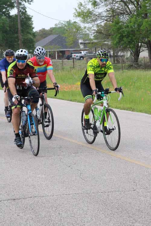 Cyclists riding together on a rural road during daytime, promoting outdoor biking and fitness.