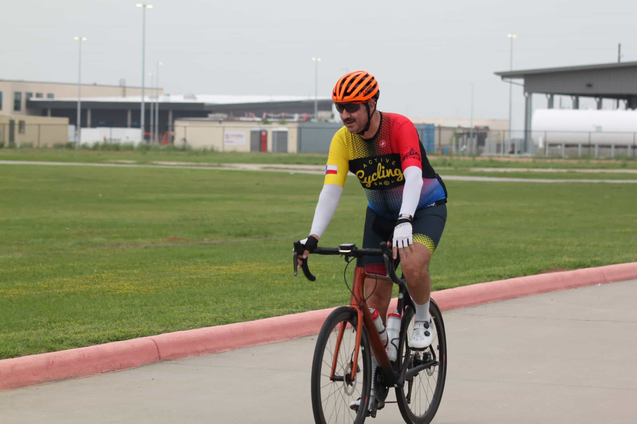 Bright cyclist riding on a paved path in active cycling gear, promoting Bluebonnet Express bike services.
