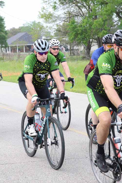 Cyclists riding together on a scenic road during Bluebonnet Express event.