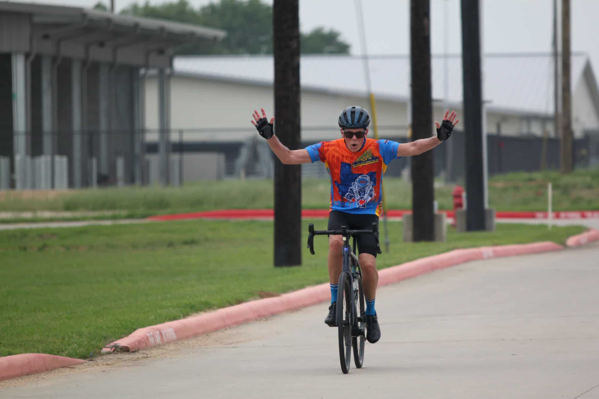 Vibrant cyclist celebrating victory after completing Bluebonnet Express bike race outdoors.