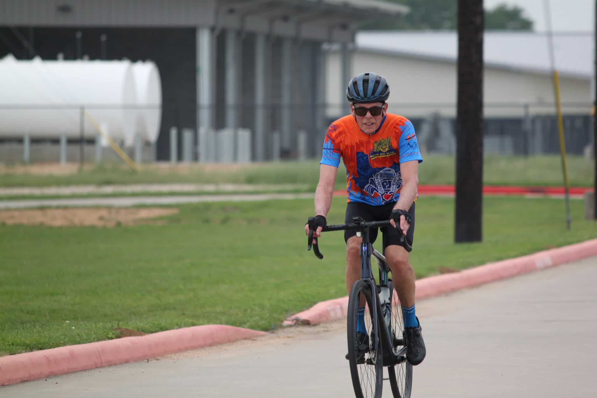 Vegan cyclist riding a bike with Bluebonnet Express branding on a paved trail.