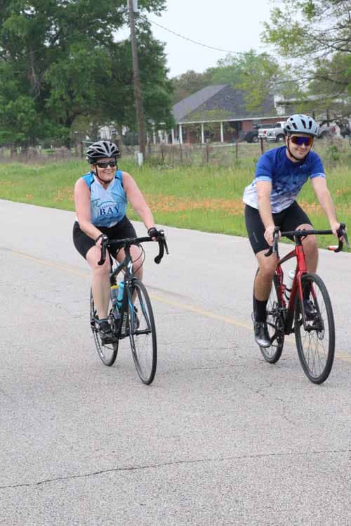 Comfortable cyclists riding on a rural road promoting Bluebonnet Express bike events.