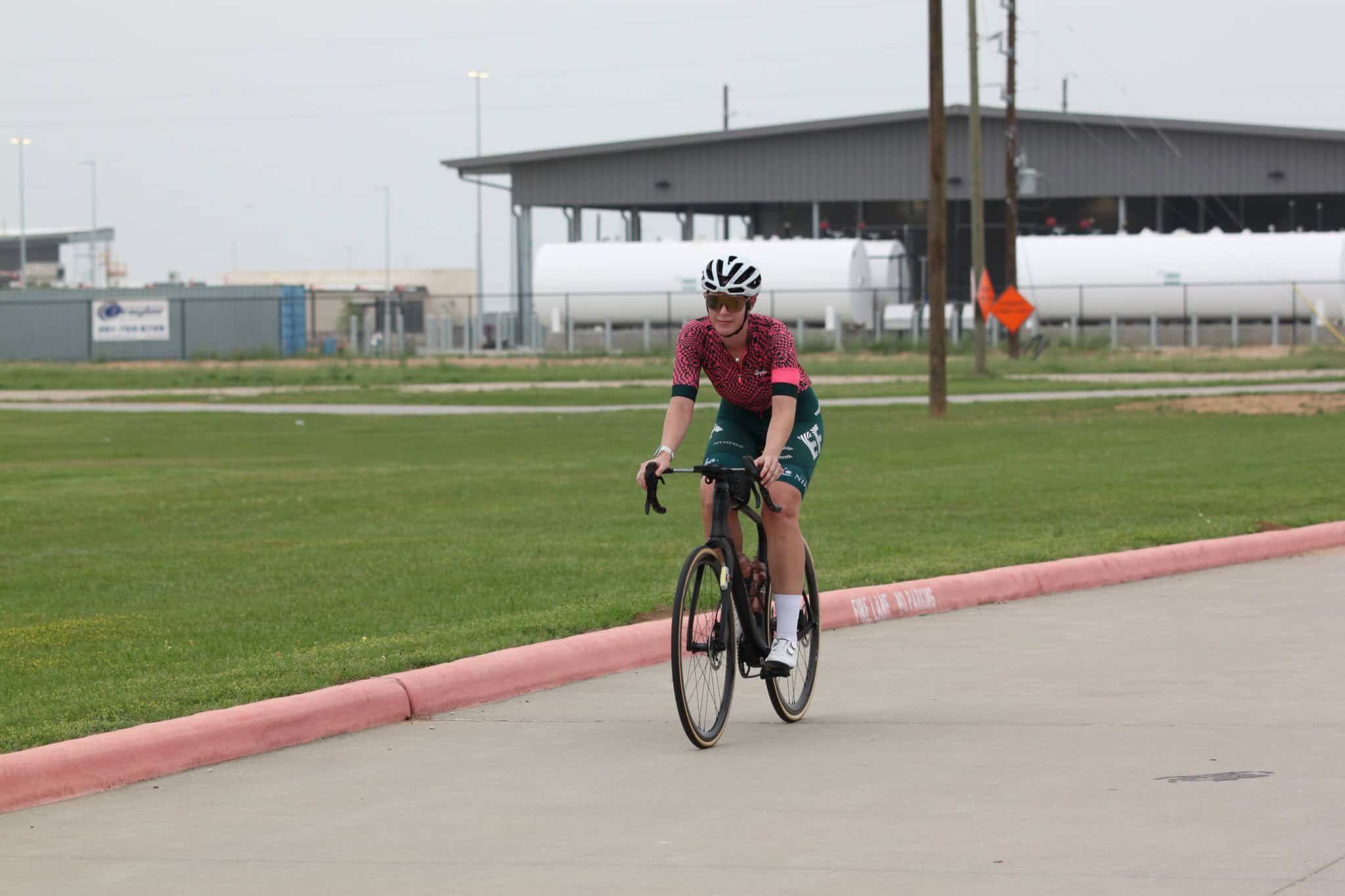 Bright female cyclist riding a road bike outdoors at Bluebonnet Express event.