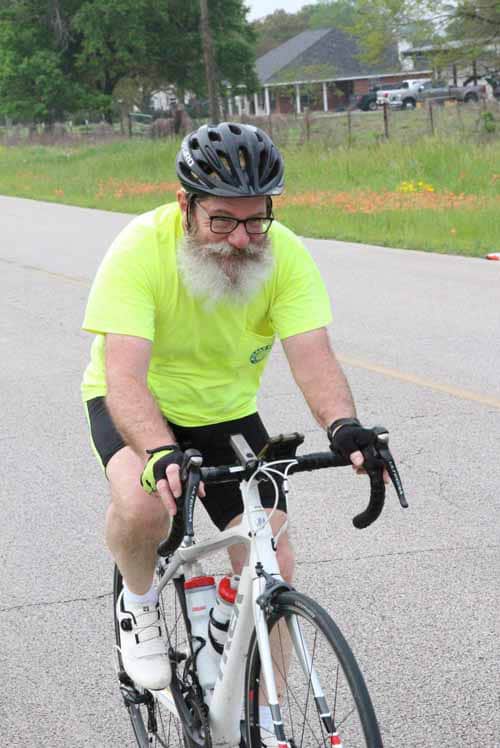 1. Man in high-visibility cycling gear riding a road bike on a city street.