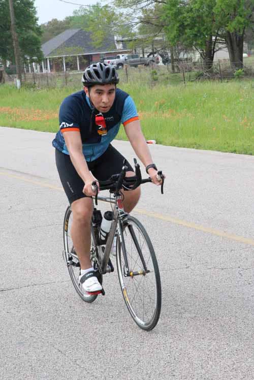 Young man riding a bicycle on the road during daytime for fitness and outdoor recreation.