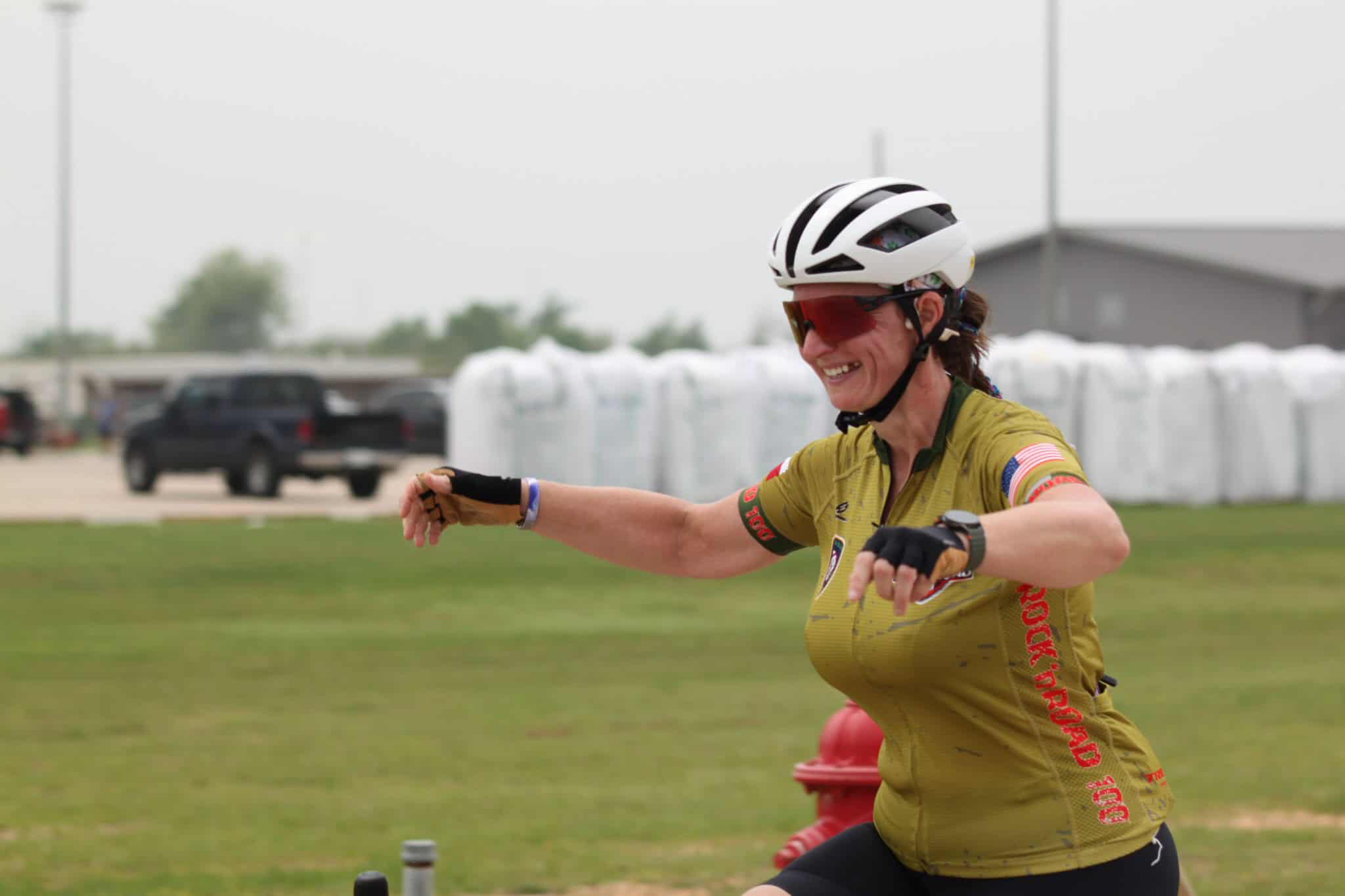 Smiling female cyclist in helmet and sunglasses during Bluebonnet Express event, enjoying bike race camaraderie.