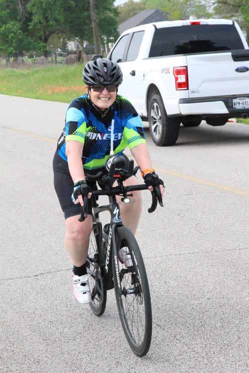 Bike rider smiling on a road, promoting Bluebonnet Express bicycle services.