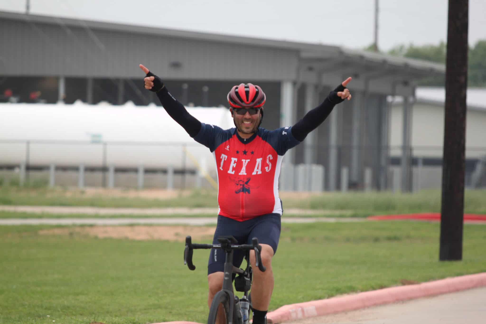Bright cyclist celebrating victory after a race at Bluebonnet Express event.