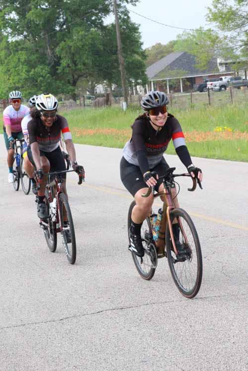 Vibrant women cyclists riding on a scenic rural road during Bluebonnet Express event.