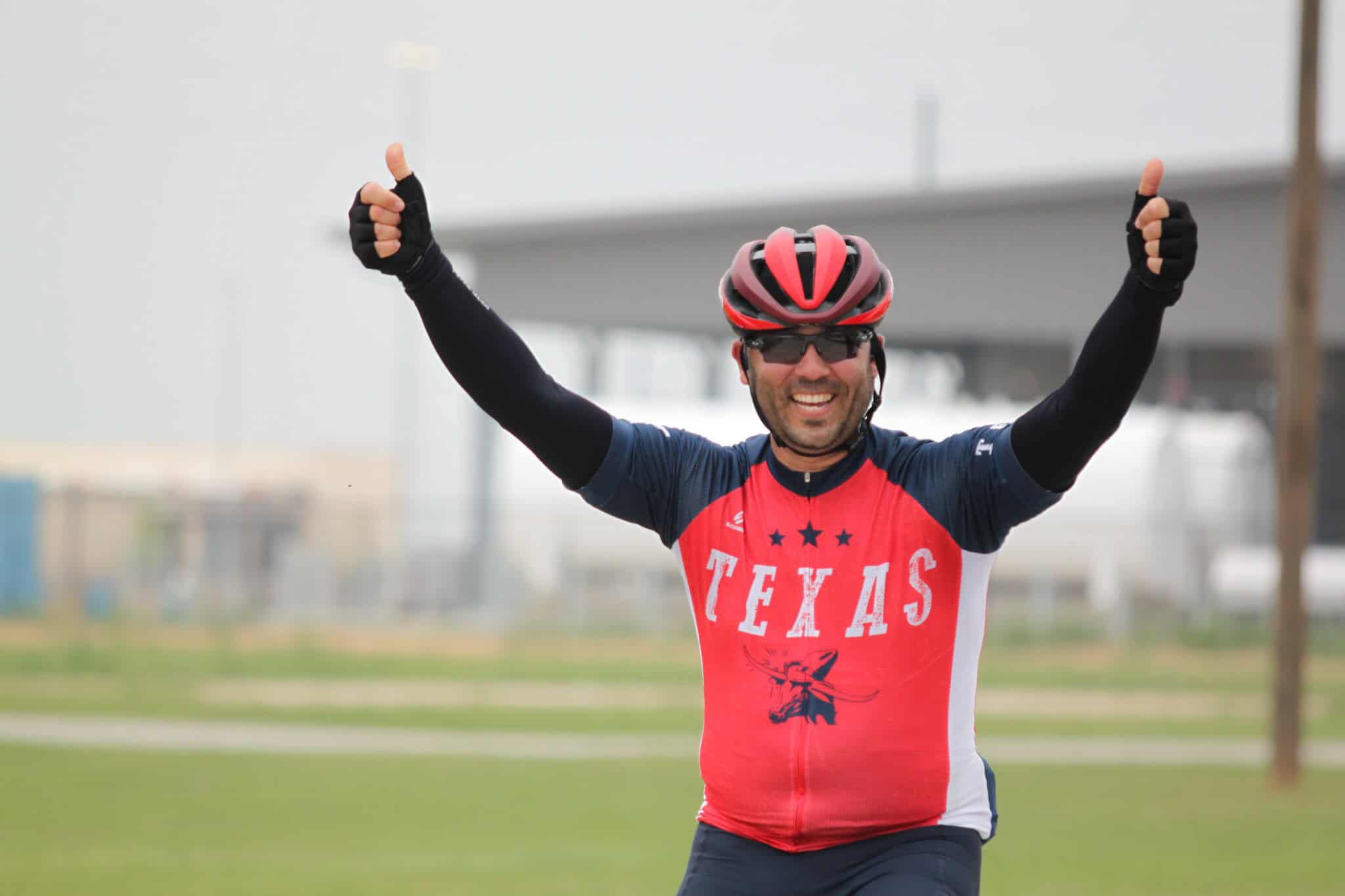 Happy cyclist in Texas cycling jersey celebrating outdoors.