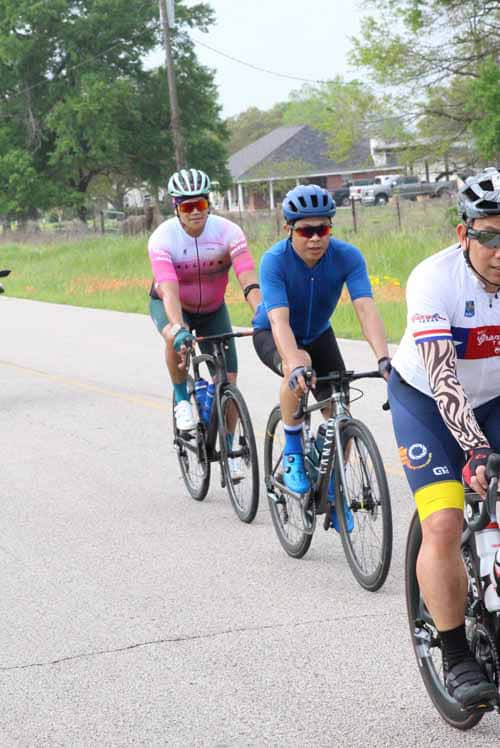 Vibrant cyclists enjoying a ride on a rural road, promoting Bluebonnet Express cycling event.