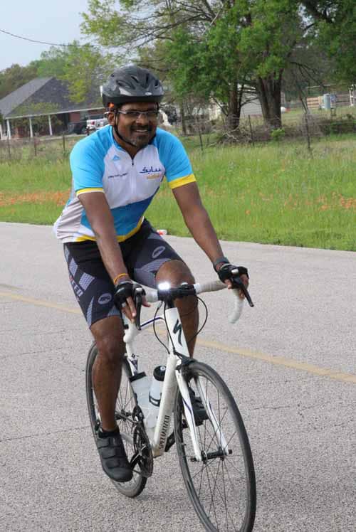 Bright-eyed cyclist enjoying a ride on a scenic road with lush greenery in the background.