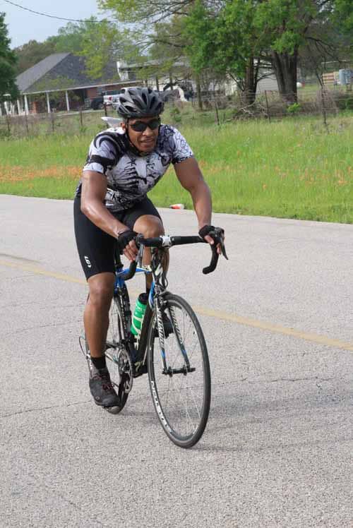 High-energy cyclist riding through scenic countryside with Bluebonnet Express branding.