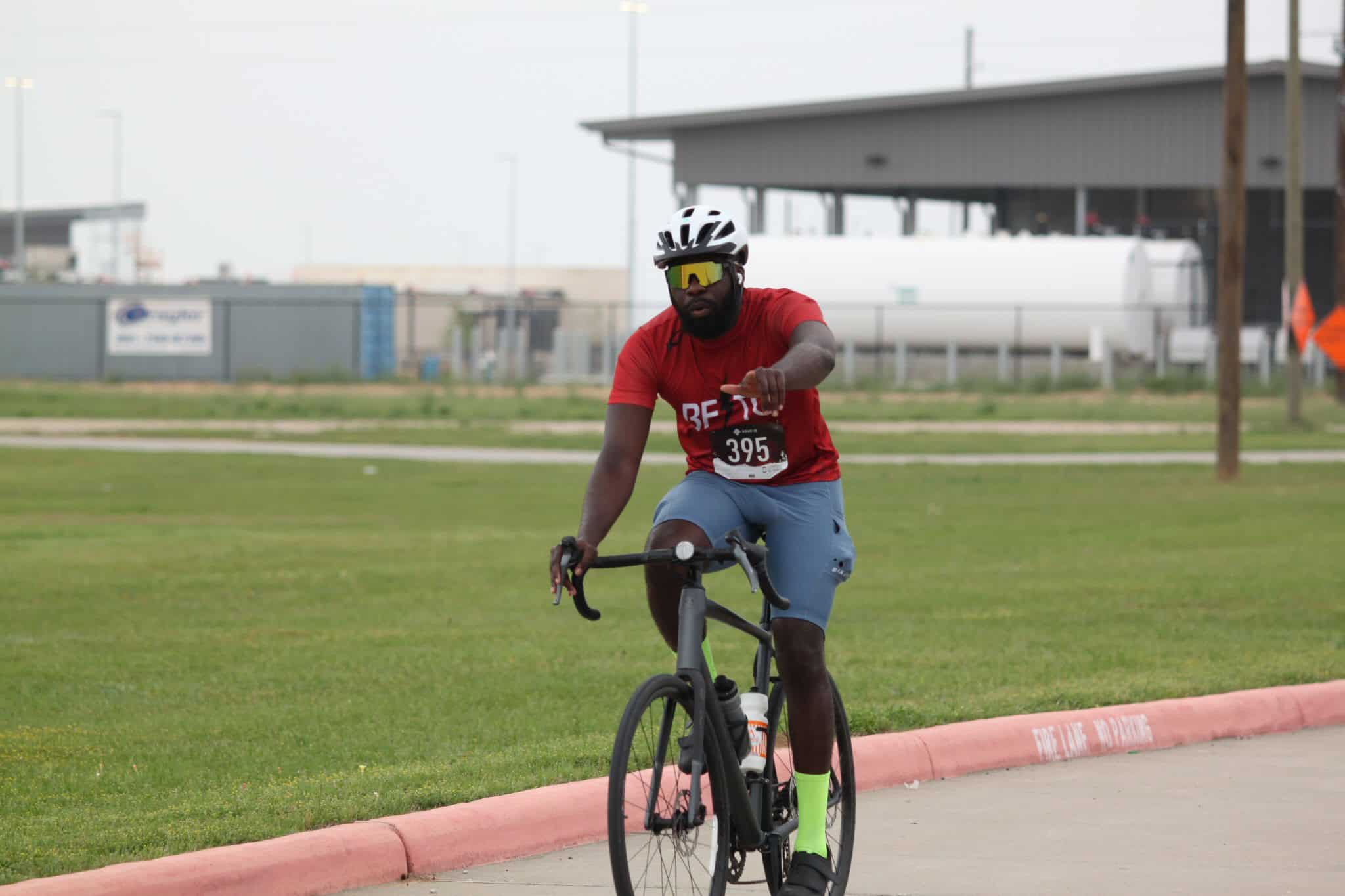 Vibrant cyclist riding on a designated bike path with industrial background, showcasing endurance and outdoor fitness.