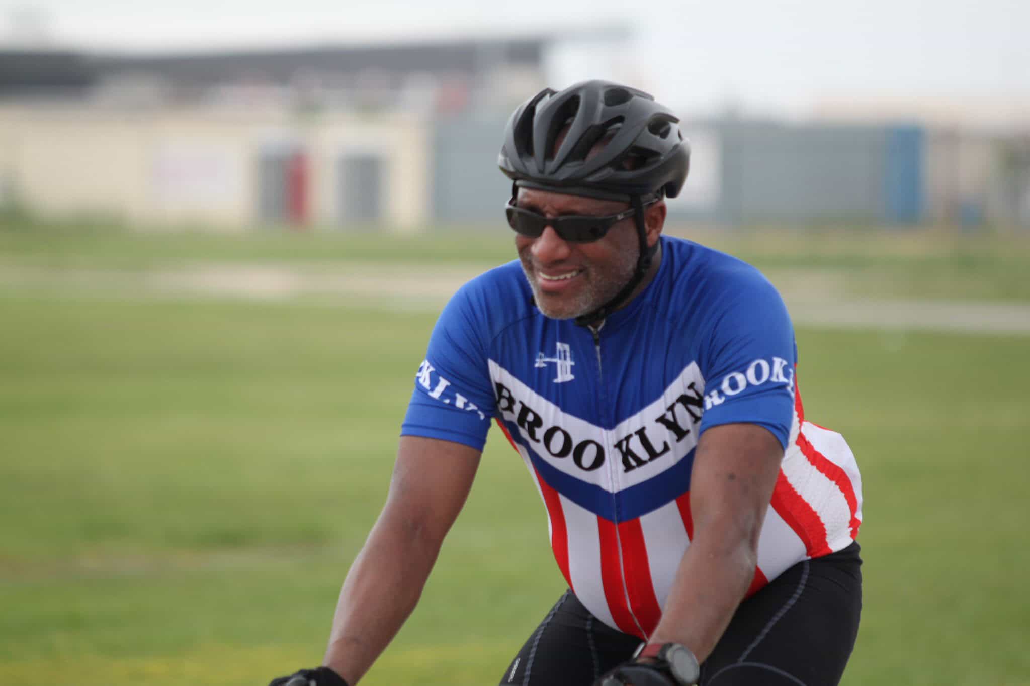 Vibrant man cycling outdoors in Bluebonnet Express cycling jersey, sunny day, active lifestyle, promoting fitness and health.