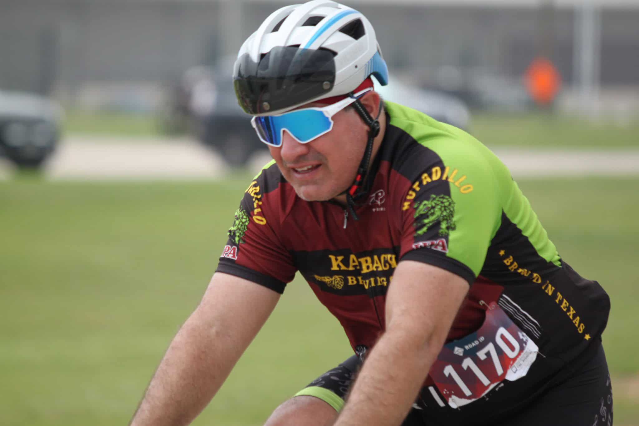 Vibrant cyclist wearing a helmet and sunglasses, participating in a cycling event on a grassy field.