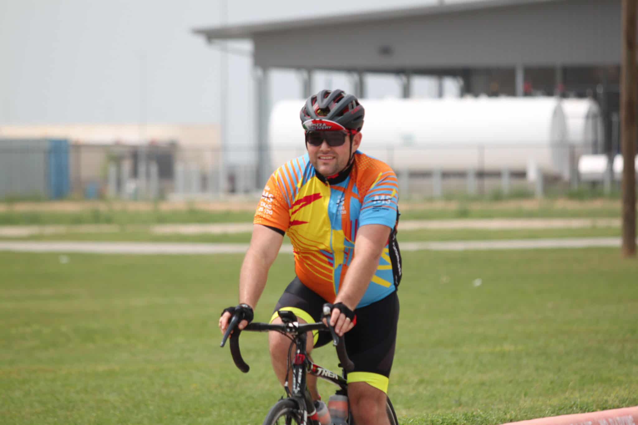 Vibrant cyclist in Bluebonnet Express jersey riding on green field, promoting Texas bike tours.