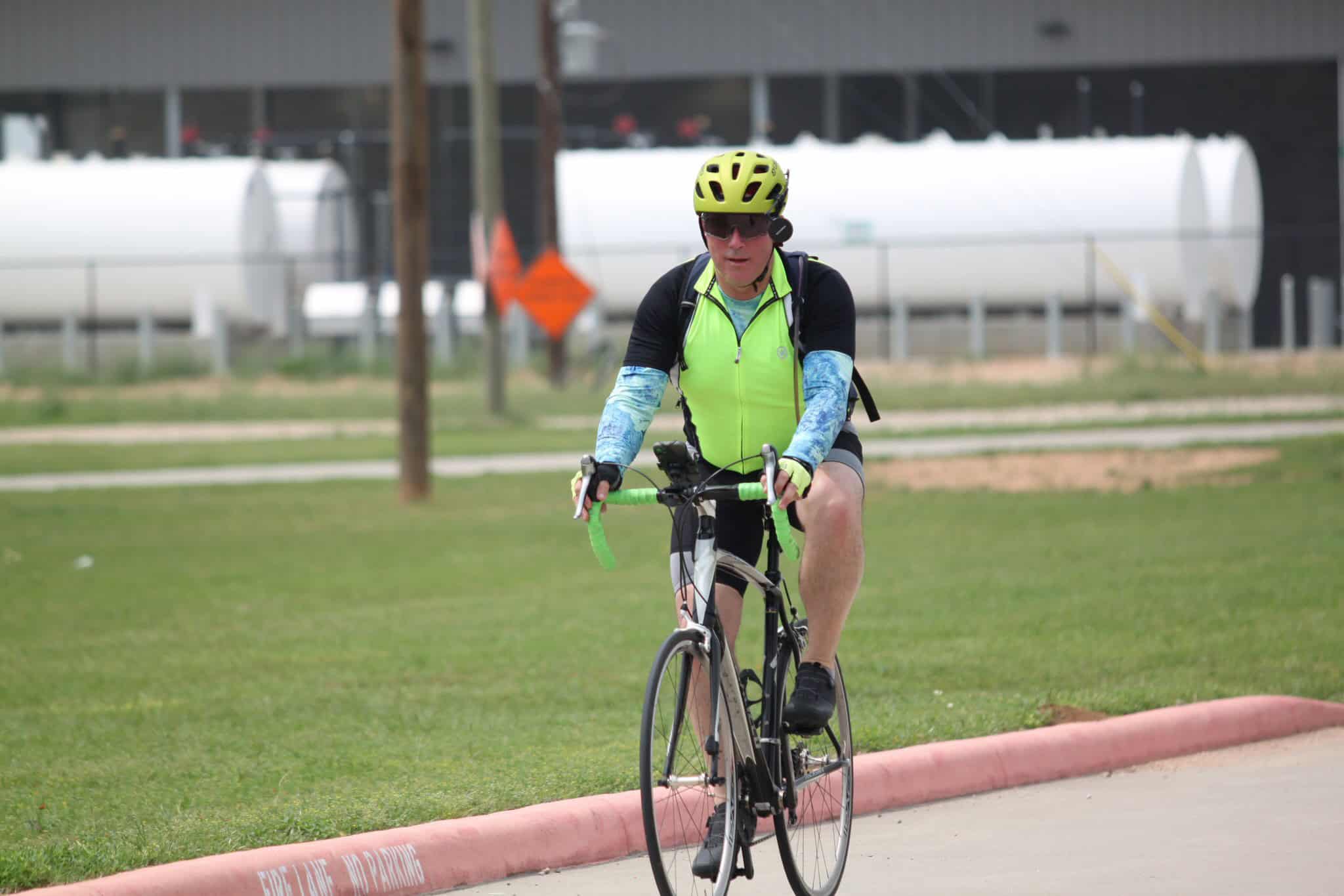 Bright yellow helmet, cycling gear, riding a bike on the street in Texas.