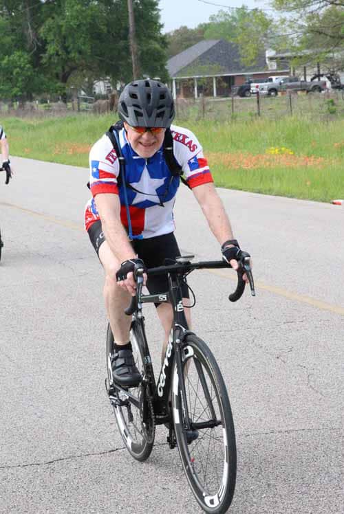 1. Man riding a bike during Bluebonnet Express cycling event in Texas, wearing patriotic jersey.