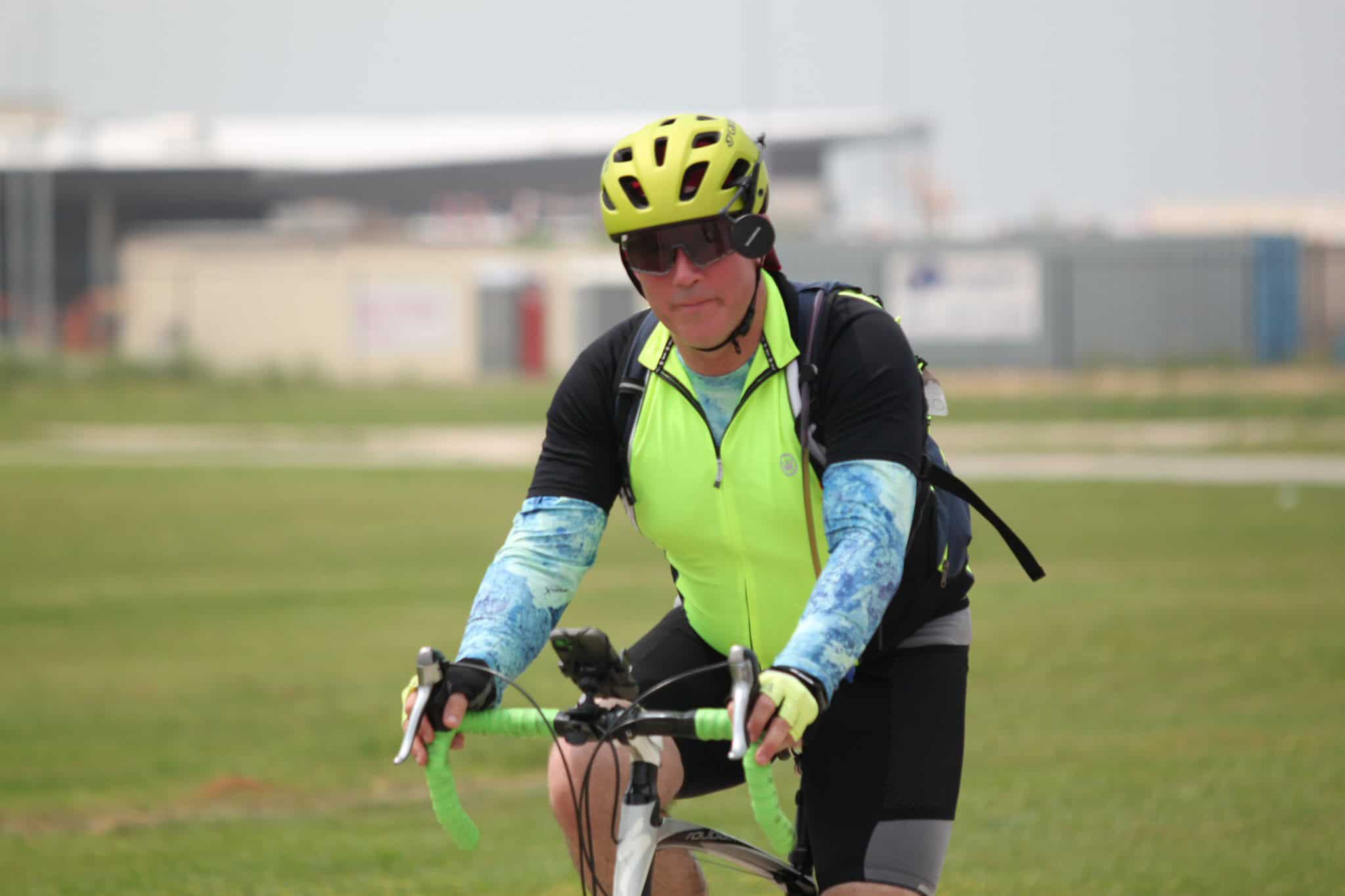 High-visibility cycling rider wearing helmet and sunglasses on a scenic outdoor route.