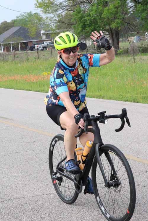 Bright green cycling helmet on smiling woman riding a black road bike outdoors.