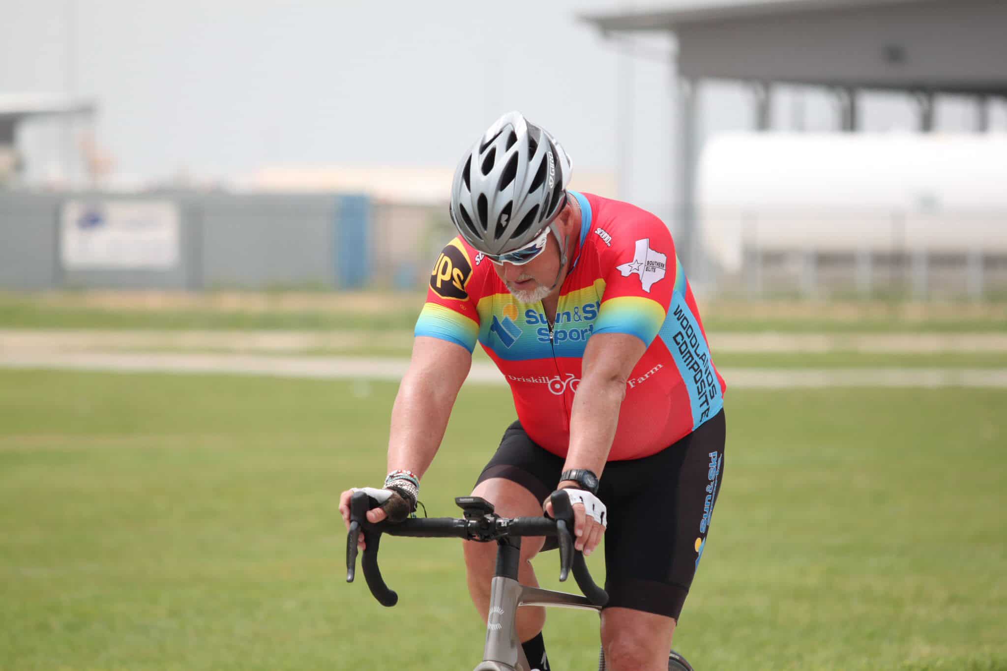 1. Male cyclist wearing a colorful jersey and helmet riding a bike outdoors.