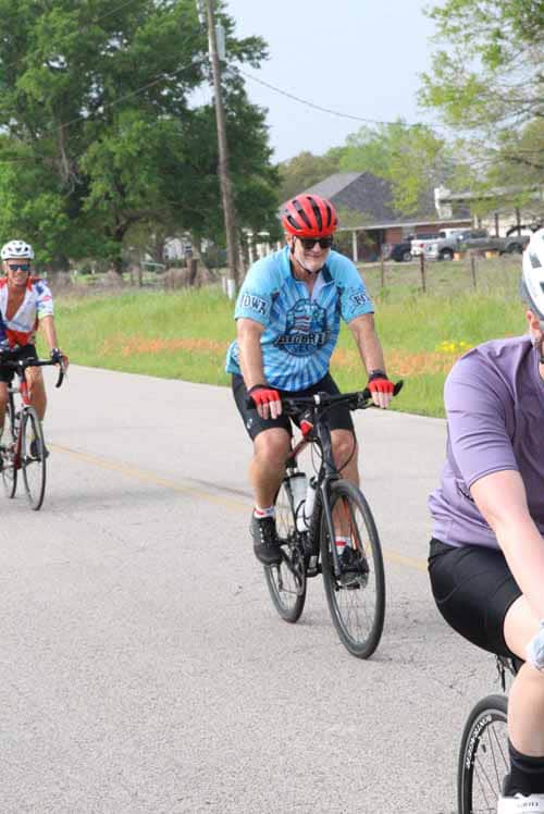 Bright cyclist wearing blue jersey and red helmet riding in Bluebonnet Express event, enjoying outdoor biking.