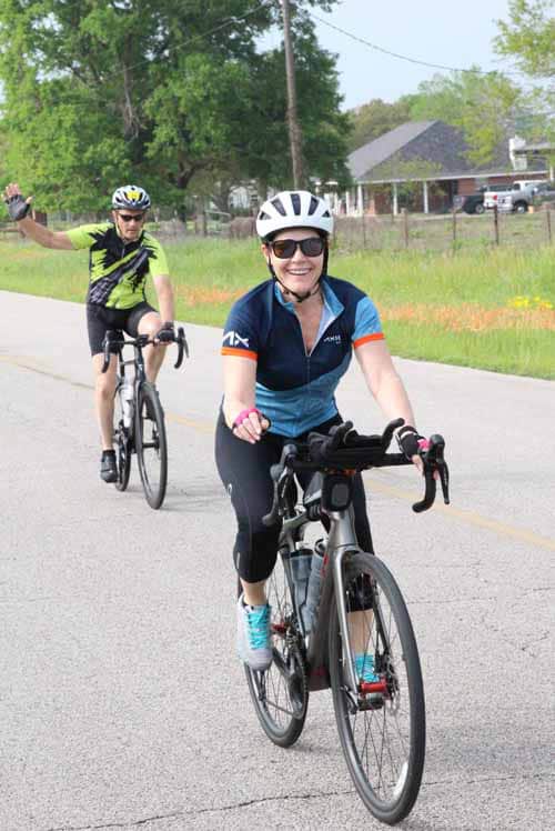 Bright woman cycling on road with friends during daytime, enjoying outdoor bike ride in community area.