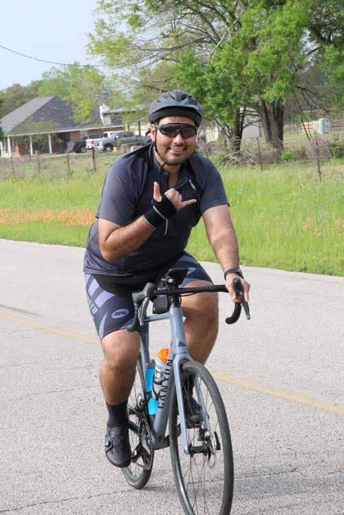 1. Smiling cyclist wearing helmet riding a bike on rural road during daytime.