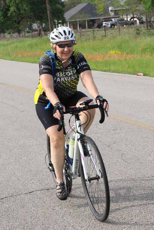 Smiling woman riding a bike during the Bluebonnet Express cycling event in Texas.