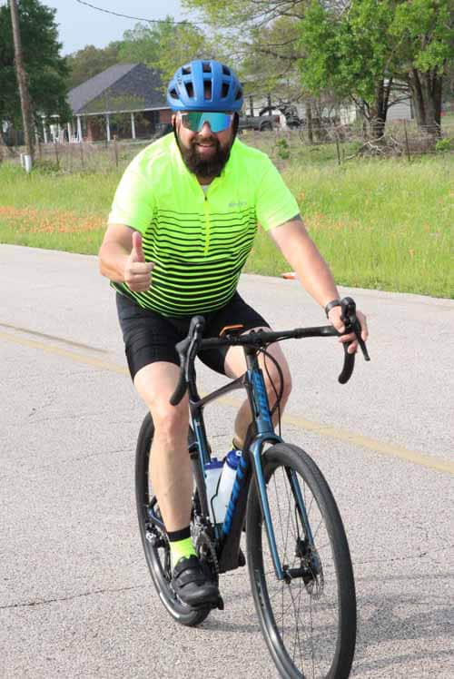 Vegan cyclist wearing neon shirt and helmet enjoying Bluebonnet Express bike ride outdoors.