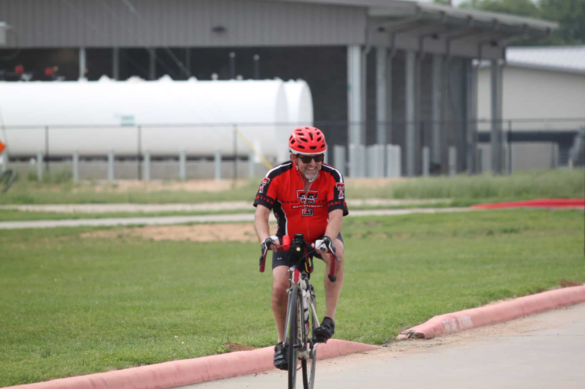 Vibrant cyclist riding on grassy path during daytime, promoting Bluebonnet Express bike event.