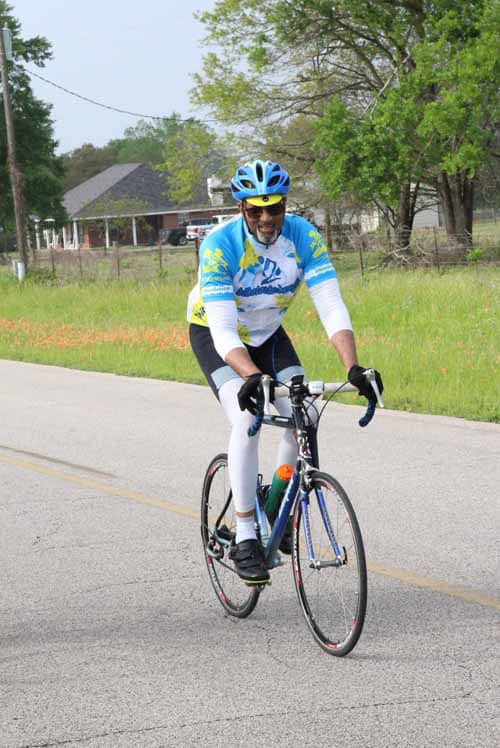 Bright blue cyclist jersey and helmet on scenic road ride, promoting Bluebonnet Express bike event.