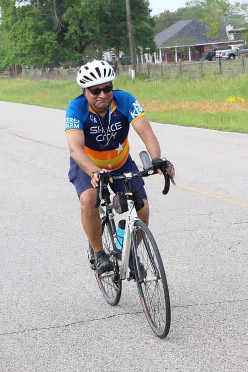 Comfortable cyclist riding on scenic road with bike helmet and athletic gear.