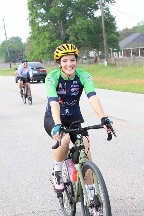 Smiling female cyclist riding during Bluebonnet Express event on a sunny day.