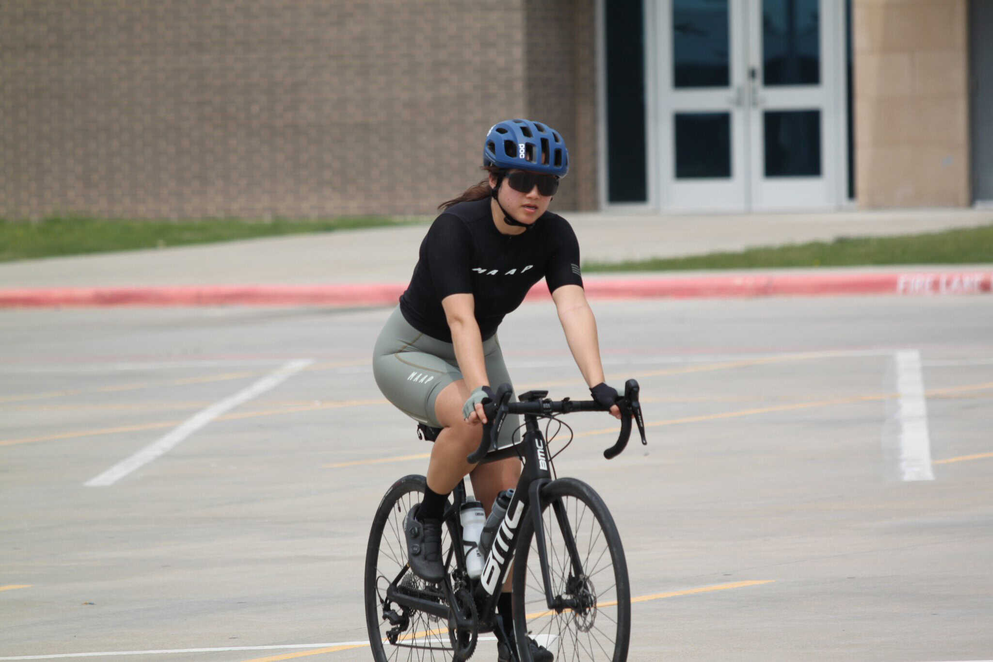 Bluebonnet Express cycling team member on a road bike in a parking lot.
