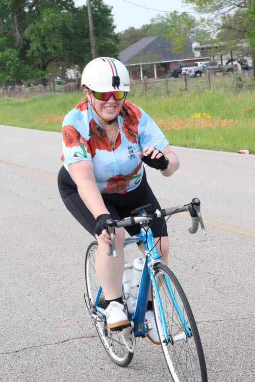 Bright female cyclist enjoying riding the Bluebonnet Express bike in scenic outdoor setting.