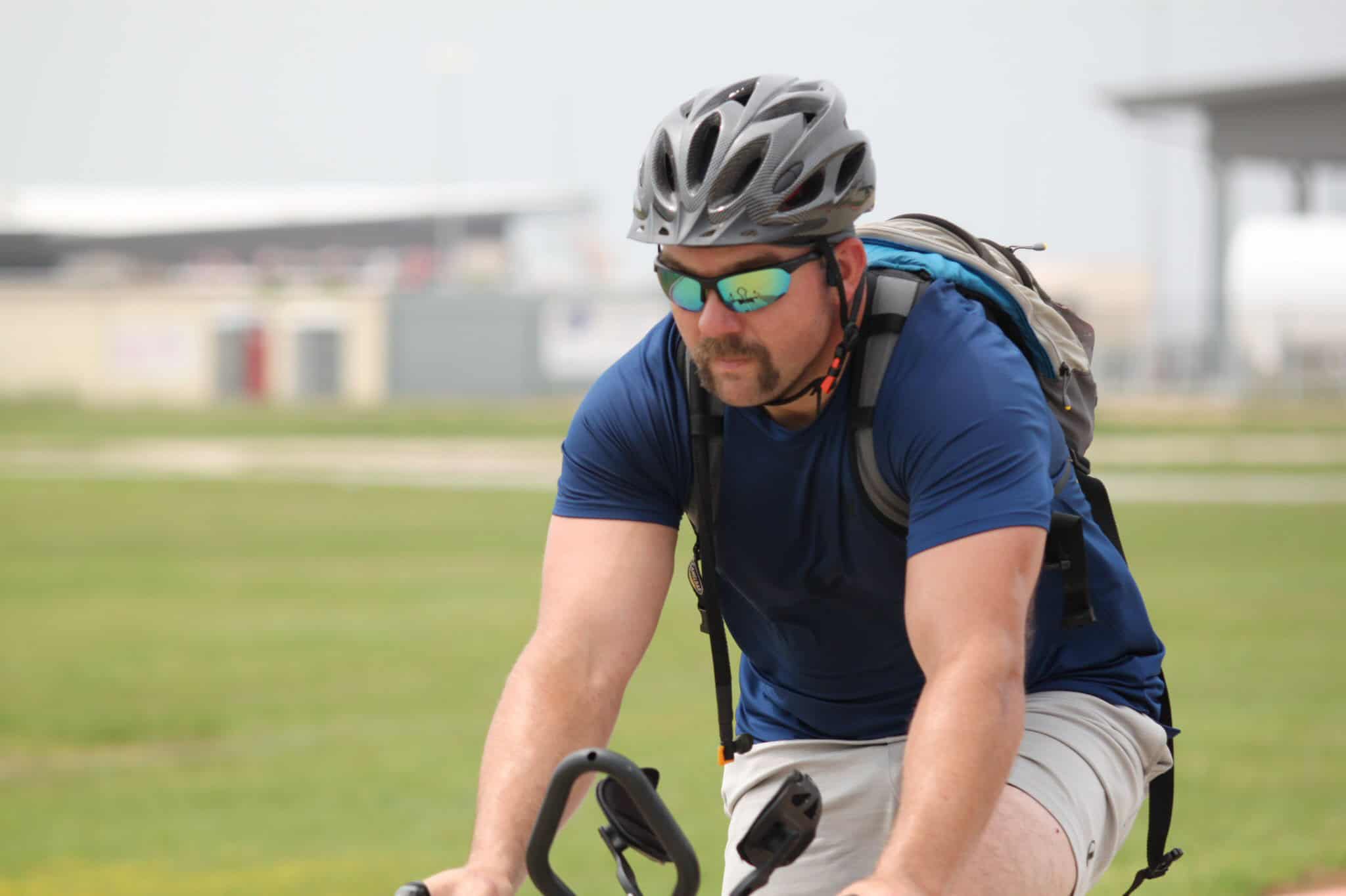 High-performance cyclist wearing helmet and sunglasses on outdoor trail.