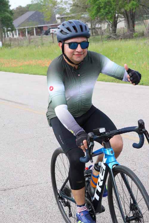 High-performance cyclist riding on scenic road in professional cycling gear and helmet.
